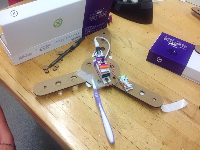 photo of the drawbot frame and little bits hardware. The drawbot is a cardboard frame with 3 arms coming out of the middle with holes that various markers can be placed in